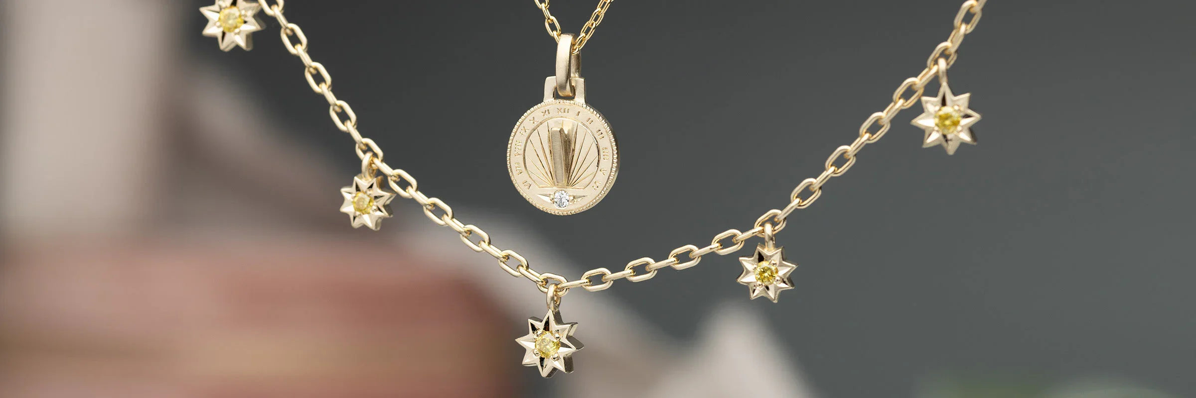 Hand-fabricated gold sundial pendant and star charms necklace, soft natural lighting on neutral background